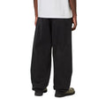 Detalle trasero del Carhartt WIP Landon Pant black tone washed sobre modelo, mostrando los bolsillos traseros y la anchura de la pernera en movimiento.