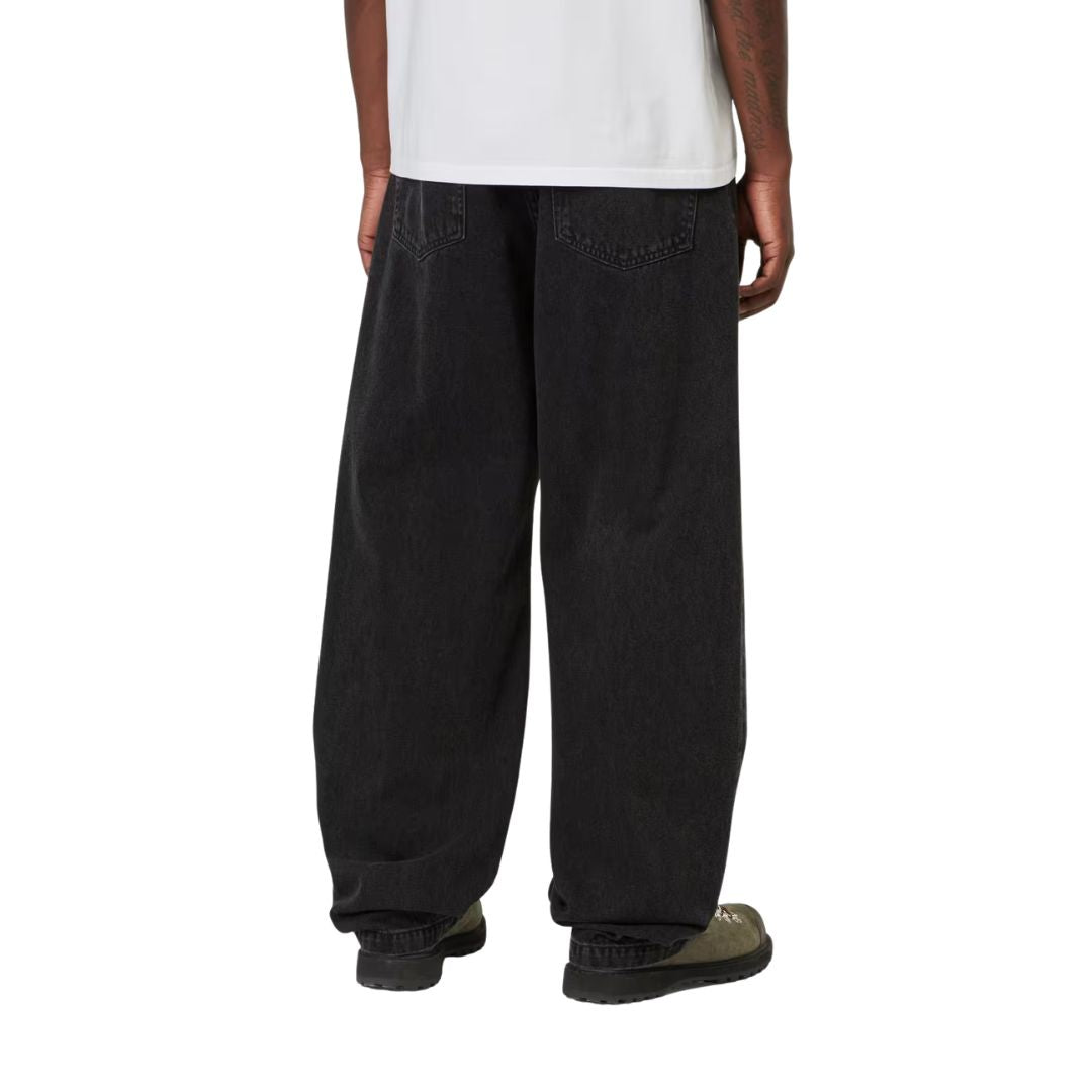 Detalle trasero del Carhartt WIP Landon Pant black tone washed sobre modelo, mostrando los bolsillos traseros y la anchura de la pernera en movimiento.