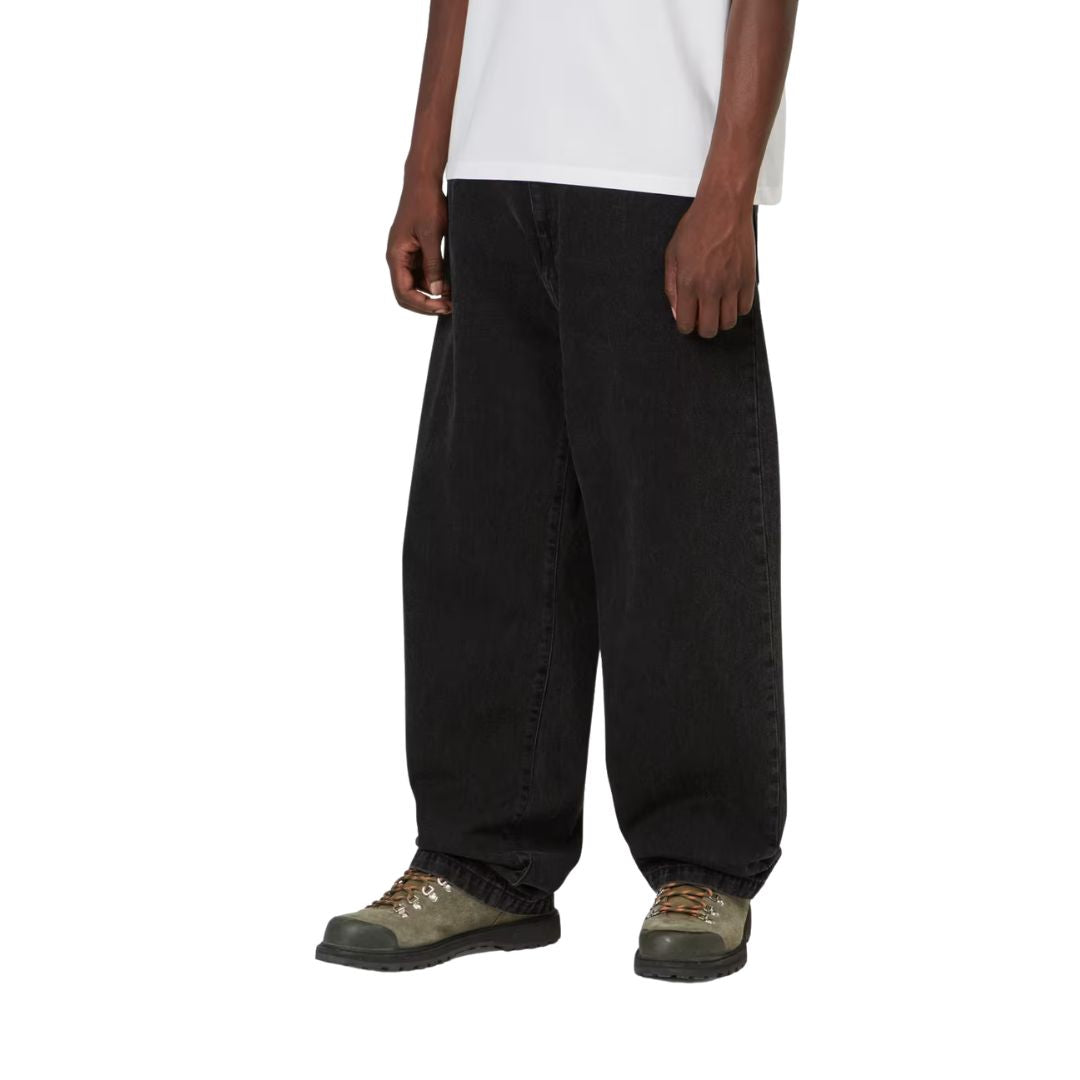 Detalle frontal del Carhartt WIP Landon Pant black tone washed sobre modelo, desde la cintura hasta el bajo, con el corte holgado y la caída del denim bien visibles.