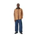 Pantalón vaquero Carhartt WIP Landon azul stone washed puesto por un modelo con chaqueta camel, mostrando el ajuste loose tapered de cintura a tobillo.
