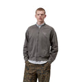 Hombre llevando chaqueta bomber Carhartt WIP gris garment dyed con cremallera frontal y bolsillos laterales.