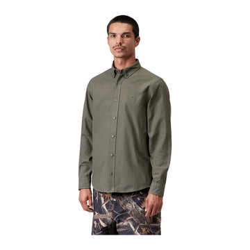 Modelo de frente con la camisa Oxford de manga larga Carhartt WIP L/S Bolton Shirt en color Shungite, con cuello abotonado, botones al frente y bolsillo en el pecho.
