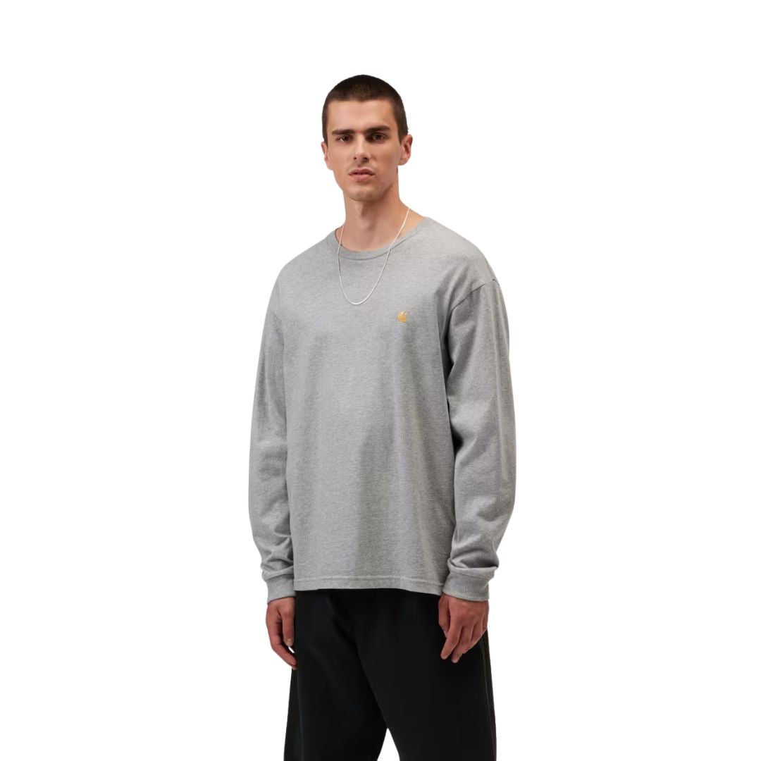 Camiseta de manga larga Carhartt WIP Chase gris jaspeado puesta por un modelo en ángulo frontal, mostrando el logotipo bordado dorado en el pecho y el cuello redondo.