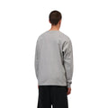 Camiseta de manga larga Carhartt WIP Chase gris jaspeado puesta por un modelo, vista trasera, combinada con pantalón negro, mostrando el corte oversize de espalda.