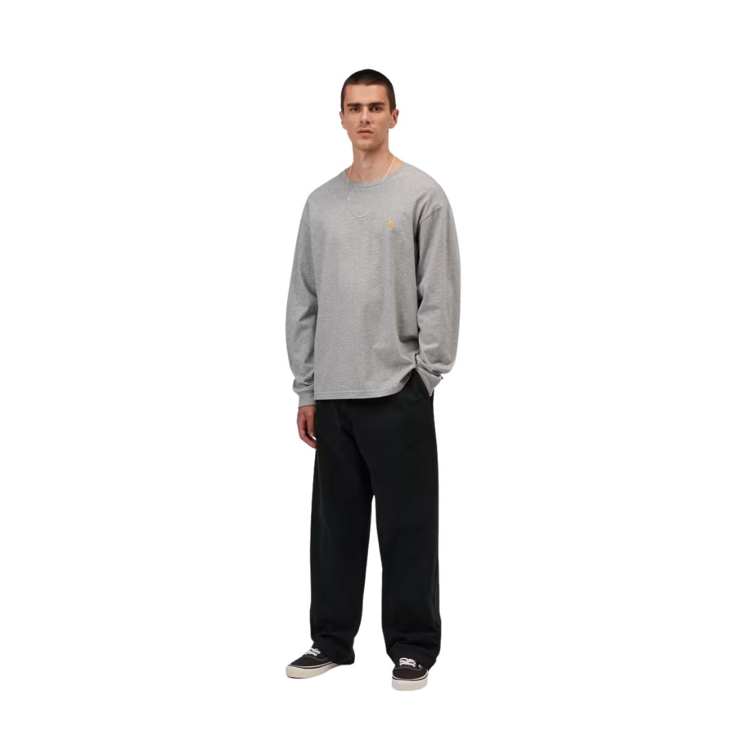 Camiseta de manga larga Carhartt WIP Chase gris jaspeado puesta por un modelo, combinada con pantalón negro y zapatillas, mostrando el ajuste oversize.