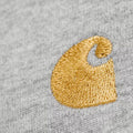 Camiseta Carhartt WIP Chase de manga larga en gris jaspeado, primer plano extremo del logotipo bordado en hilo dorado que representa el icónico parche en forma de C de la marca.