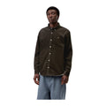 Modelo de frente con la camisa de pana de manga larga Carhartt WIP L/S Madison Cord Shirt en color Tobacco, con cuello abotonado y logotipo bordado en el pecho.