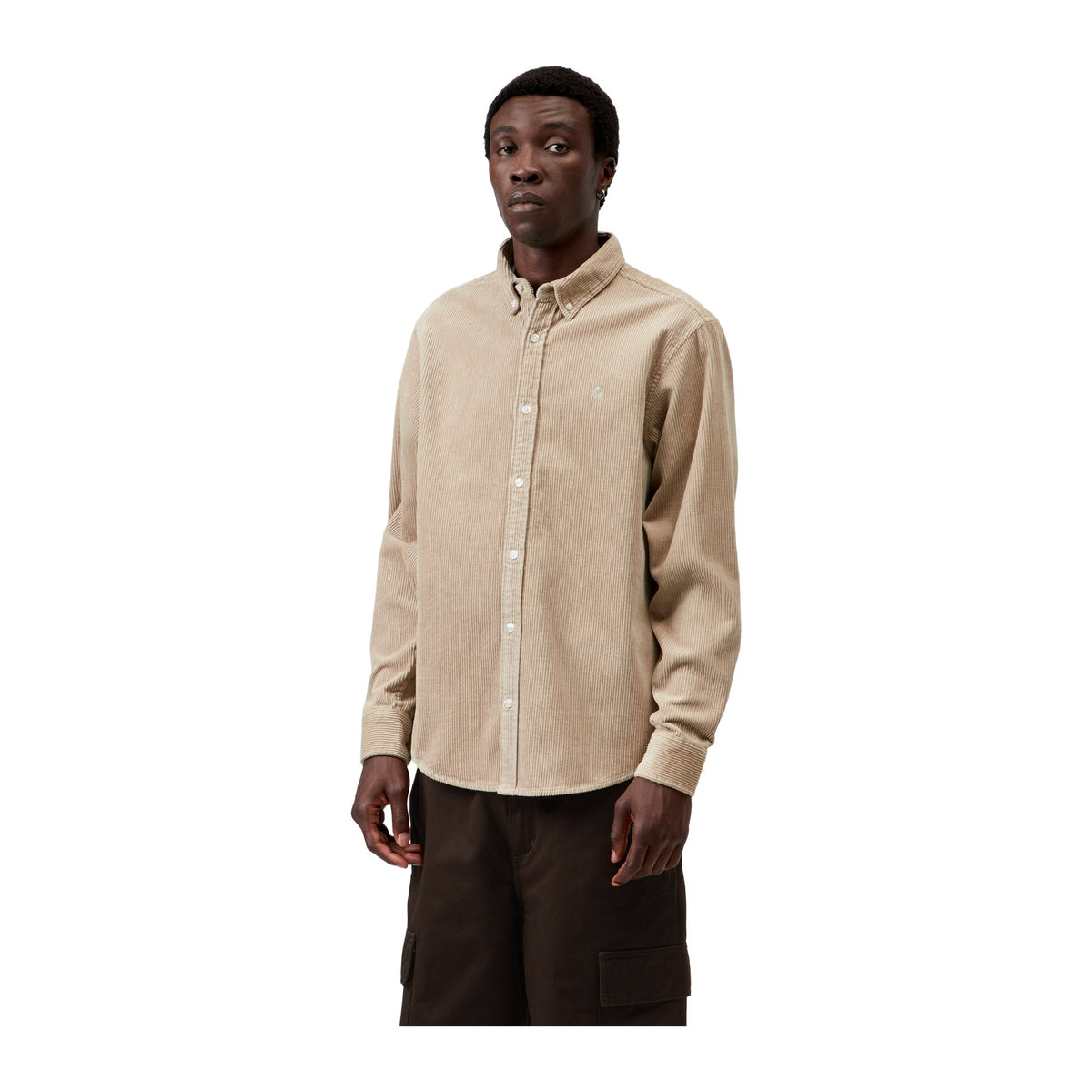 Modelo de frente con la camisa de pana de manga larga Carhartt WIP L/S Madison Cord Shirt en color Wall, beige claro con cuello abotonado y bordado en el pecho.