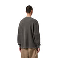 Modelo con Carhartt WIP L/S Vista Waffle T-Shirt en negro, vista trasera. Se aprecia la caída holgada del tejido gofrado y el largo de manga sobre la muñeca.