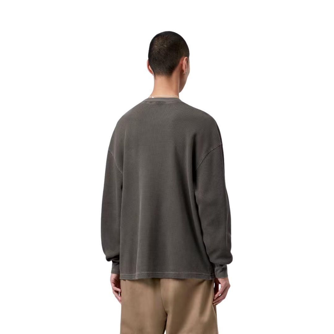 Modelo con Carhartt WIP L/S Vista Waffle T-Shirt en negro, vista trasera. Se aprecia la caída holgada del tejido gofrado y el largo de manga sobre la muñeca.