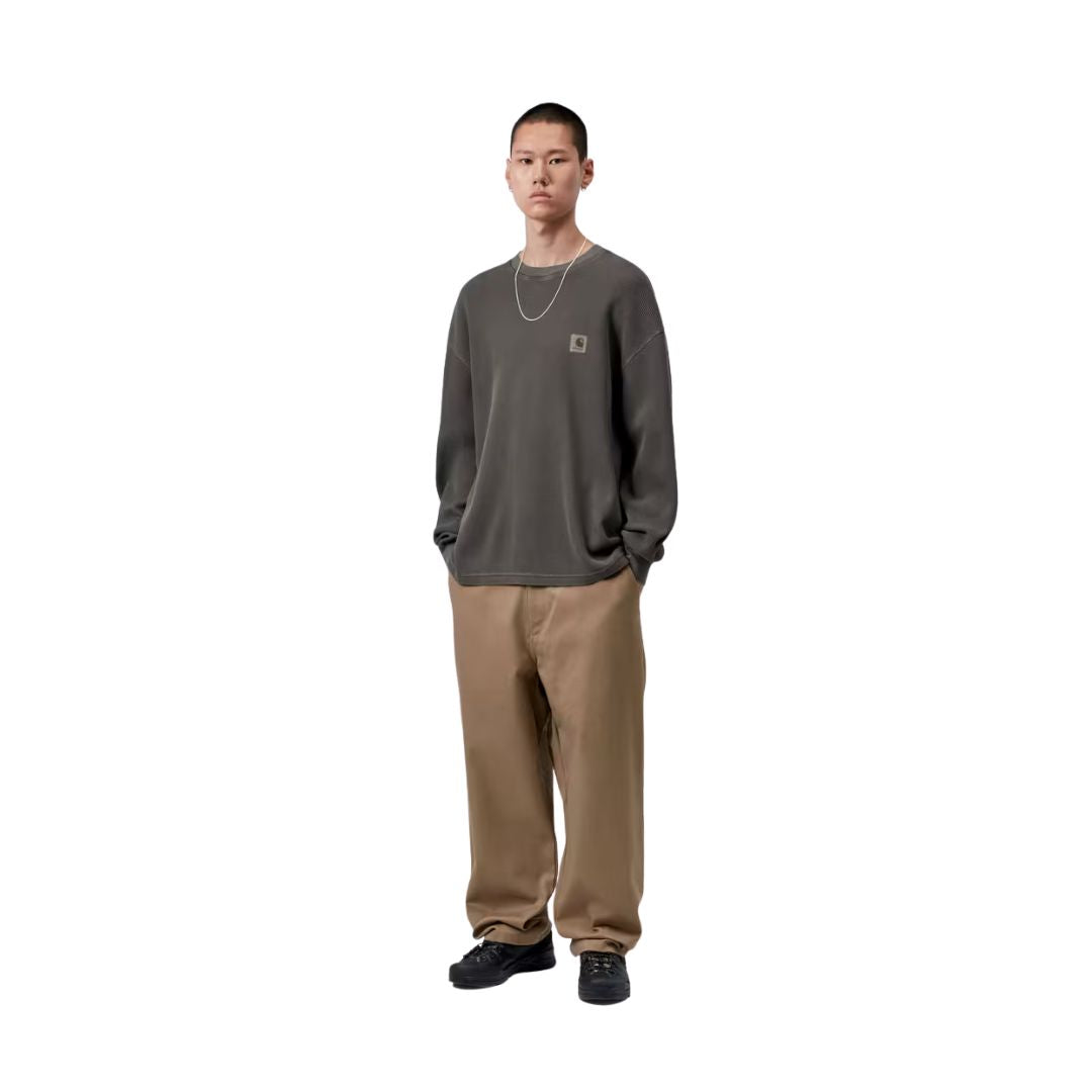 Modelo con Carhartt WIP L/S Vista Waffle T-Shirt en negro, vista frontal completa. Combina la camiseta de manga larga con pantalón chino ancho, mostrando el ajuste holgado de la prenda.