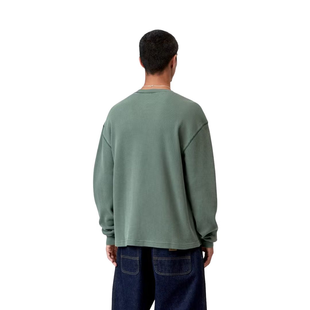 Modelo con Carhartt WIP L/S Vista Waffle T-Shirt en verde dark scarab, vista trasera. Se aprecia la caída holgada del tejido gofrado sobre vaquero azul oscuro.