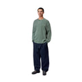 Modelo con Carhartt WIP L/S Vista Waffle T-Shirt en verde dark scarab, vista frontal completa. Combina la camiseta de manga larga con vaquero ancho, mostrando el ajuste holgado de la prenda.