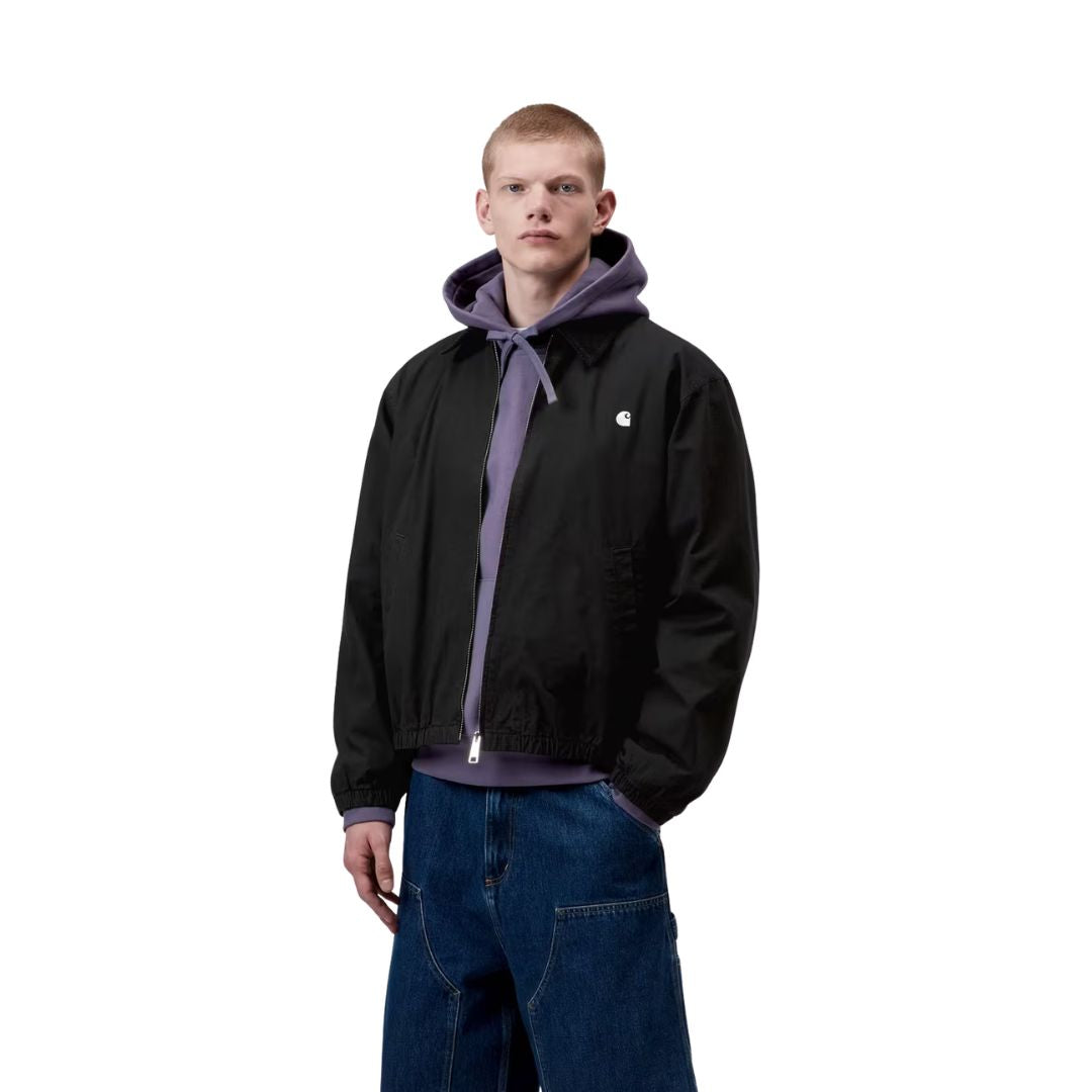 Carhartt WIP Madison Ripstop Jacket negro wax, modelo masculino de tres cuartos mostrando puño elástico y caída del tejido ripstop teñido en prenda.