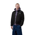 Carhartt WIP Madison Ripstop Jacket negro wax, modelo masculino de tres cuartos mostrando puño elástico y caída del tejido ripstop teñido en prenda.