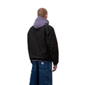 Carhartt WIP Madison Ripstop Jacket negro wax, vista trasera sobre modelo masculino destacando la espalda limpia y bajo elástico sin costuras visibles.
