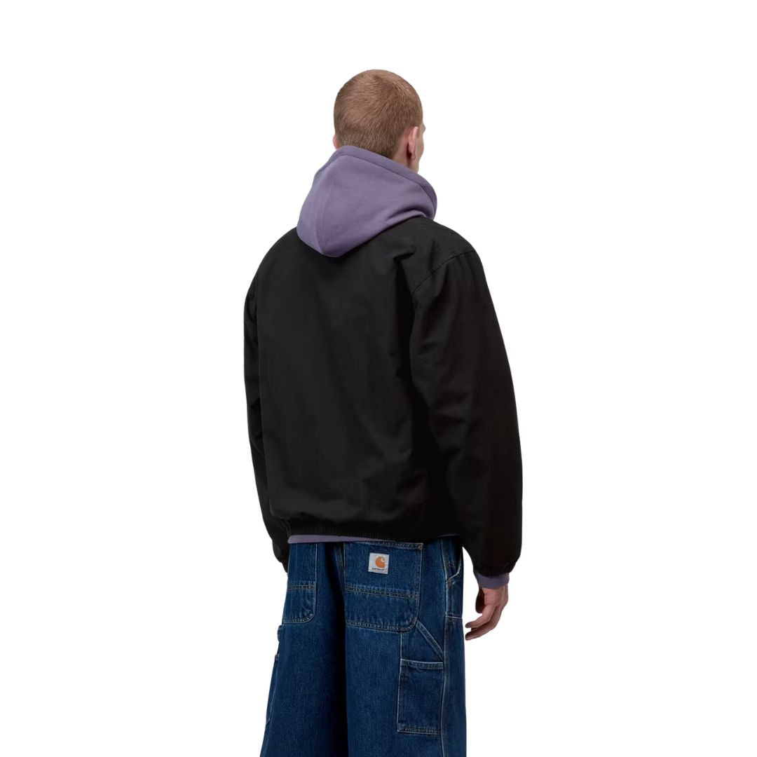 Carhartt WIP Madison Ripstop Jacket negro wax, vista trasera sobre modelo masculino destacando la espalda limpia y bajo elástico sin costuras visibles.