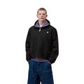 Carhartt WIP Madison Ripstop Jacket negro wax, modelo masculino de frente con cremallera cerrada y capucha lila visible, detalle del bajo elástico y bolsillo lateral.