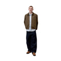 Carhartt WIP Madison Ripstop Jacket Dark Beech, modelo masculino de cuerpo entero de frente con corte relajado, camisa de rayas asomando bajo el bajo elástico.