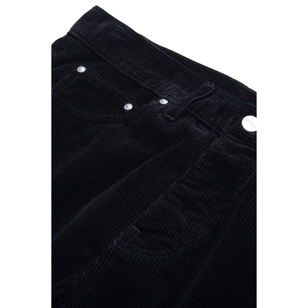 Detalle de la cintura del pantalón de pana Carhartt WIP Newel Pant en color negro: botón metálico, remaches del bolsillo delantero, trabillas y costuras sobre el canalé grueso del tejido.