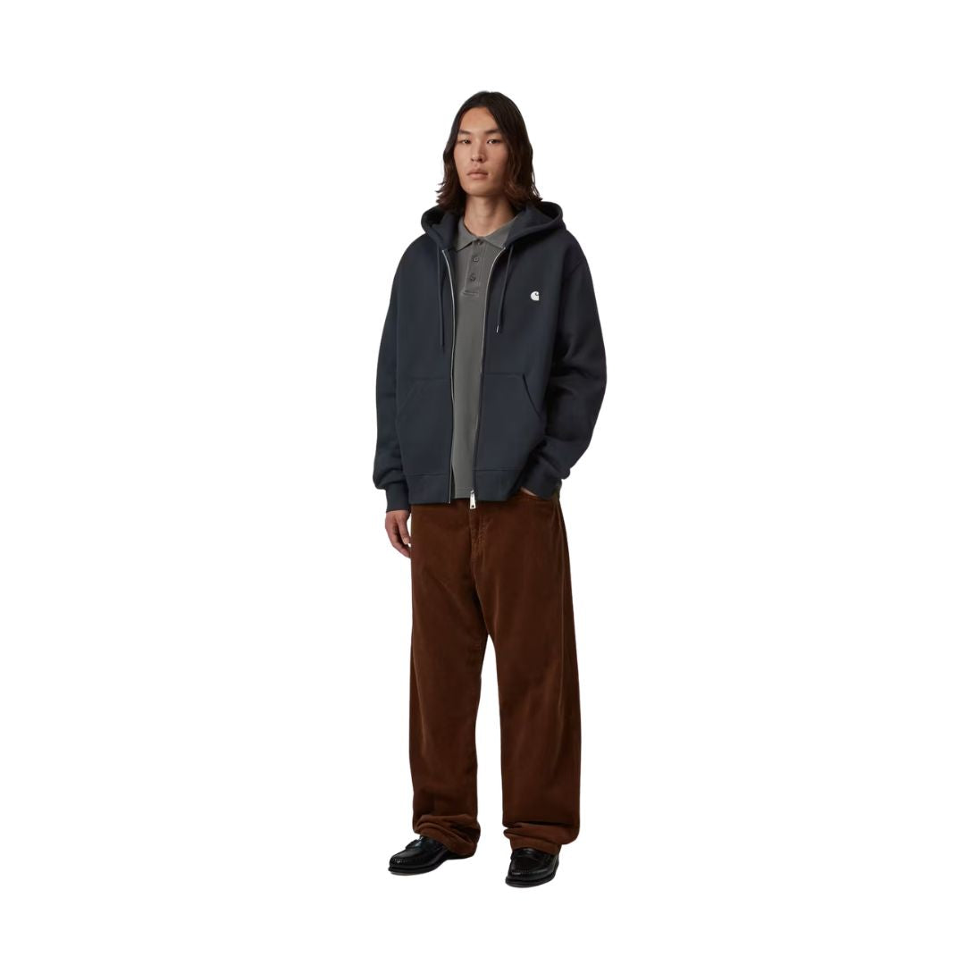 Modelo con la Carhartt WIP Hooded Mack Sweat Jacket en color dark navy wax abierta sobre un polo y con pantalón de pana holgado, mostrando de cuerpo entero el corte balloon y el ajuste loose fit.