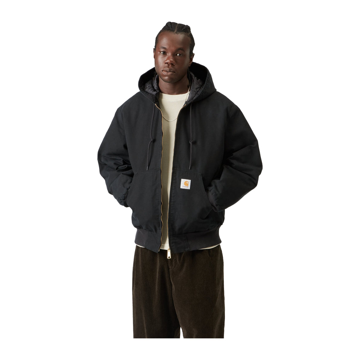 Modelo de frente con la chaqueta de lona con capucha Carhartt WIP OG Active Jacket en color Black, con cremallera, bolsillo canguro y etiqueta cuadrada en el bajo.