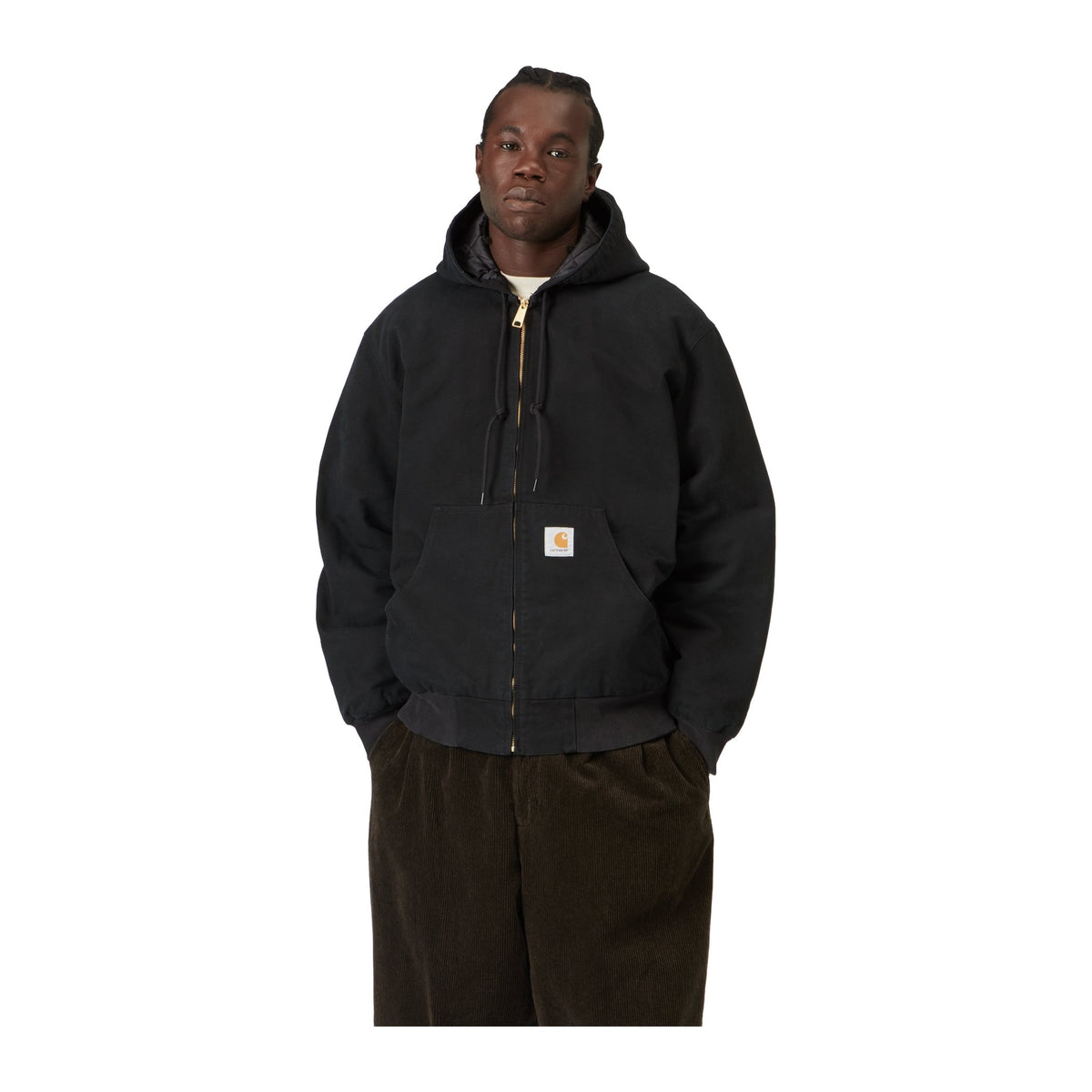 Modelo con las manos en los bolsillos y la chaqueta Carhartt WIP OG Active Jacket en color Black, con capucha, cordón de ajuste y silueta tipo bomber.