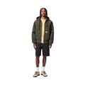 Chaqueta Carhartt WIP OG Active Jacket color oliva vista frontal con capucha y cremallera cerrada y vaqueros cortos.
