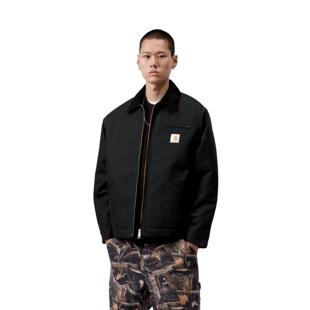 Vista frontal del modelo con la Carhartt WIP OG Detroit Jacket Winter en color negro, mostrando los hombros caídos, el cuello de pana y la banda inferior ajustable a presión