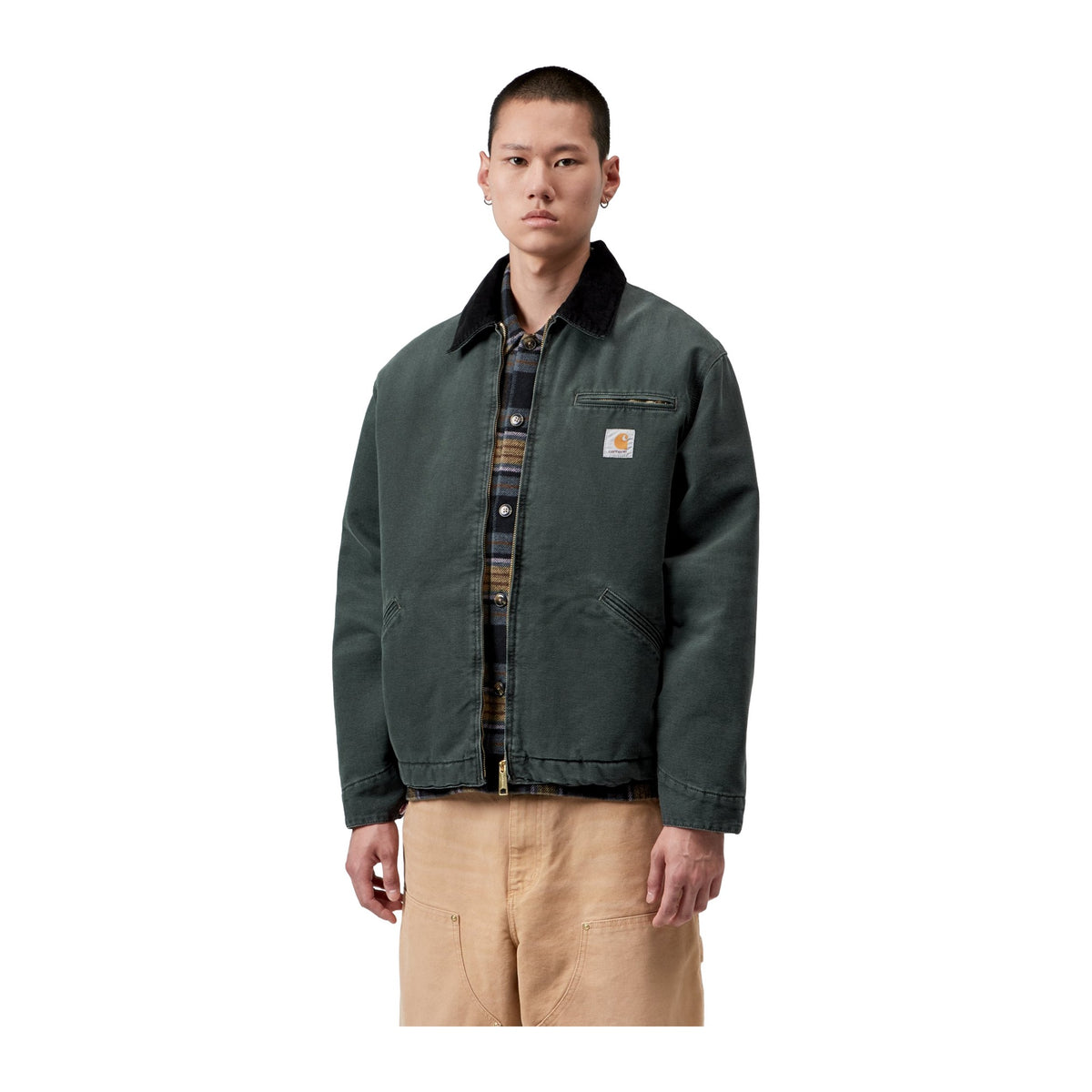 Modelo de frente con la chaqueta acolchada Carhartt WIP OG Detroit Jacket en color Raven / Black, con cuello oscuro, cremallera y etiqueta cuadrada en el pecho.