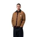 Vista frontal del modelo con la Carhartt WIP OG Detroit Jacket Winter en color marrón, mostrando los hombros caídos, el cuello de pana oscuro y la banda inferior ajustable.