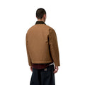 Vista trasera del modelo con la Carhartt WIP OG Detroit Jacket Winter en color marrón, mostrando los hombros caídos, el cuello de pana oscuro y la banda inferior ajustable.