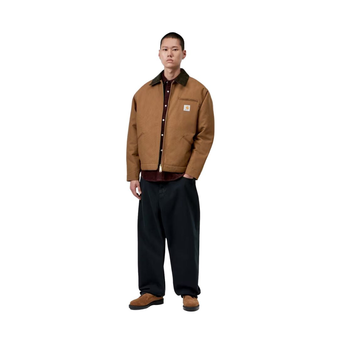 Modelo con la Carhartt WIP OG Detroit Jacket Winter en color marrón abierta sobre una camisa de pana, con pantalón negro, mostrando de cuerpo entero el corte holgado.