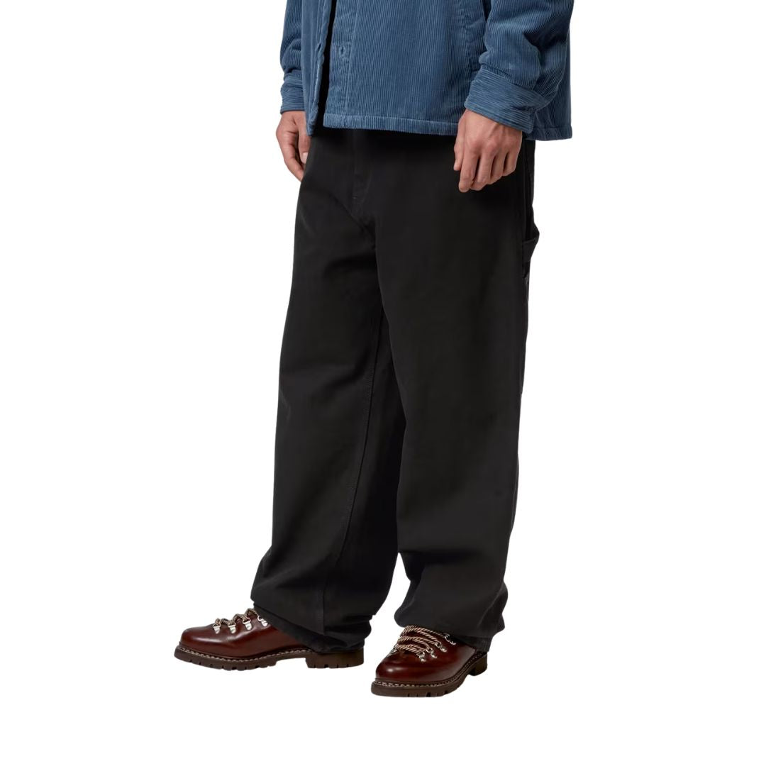 Carhartt WIP OG Single Knee Black Stone Washed vista lateral con modelo pantalón negro stone washed bolsillos utilitarios.