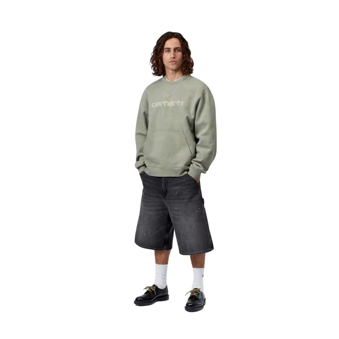 Carhartt WIP OG Single Knee Short negro destroy wash splatter, modelo cuerpo completo vista frontal, wide fit con sudadera Carhartt WIP verde sage.
