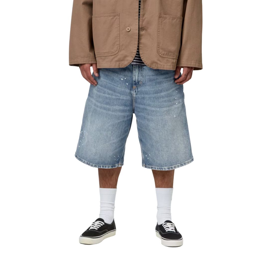 Carhartt WIP OG Single Knee Short azul destroy wash, modelo vista frontal desde cintura, denim desgastado con toques de pintura blanca y corte wide fit.