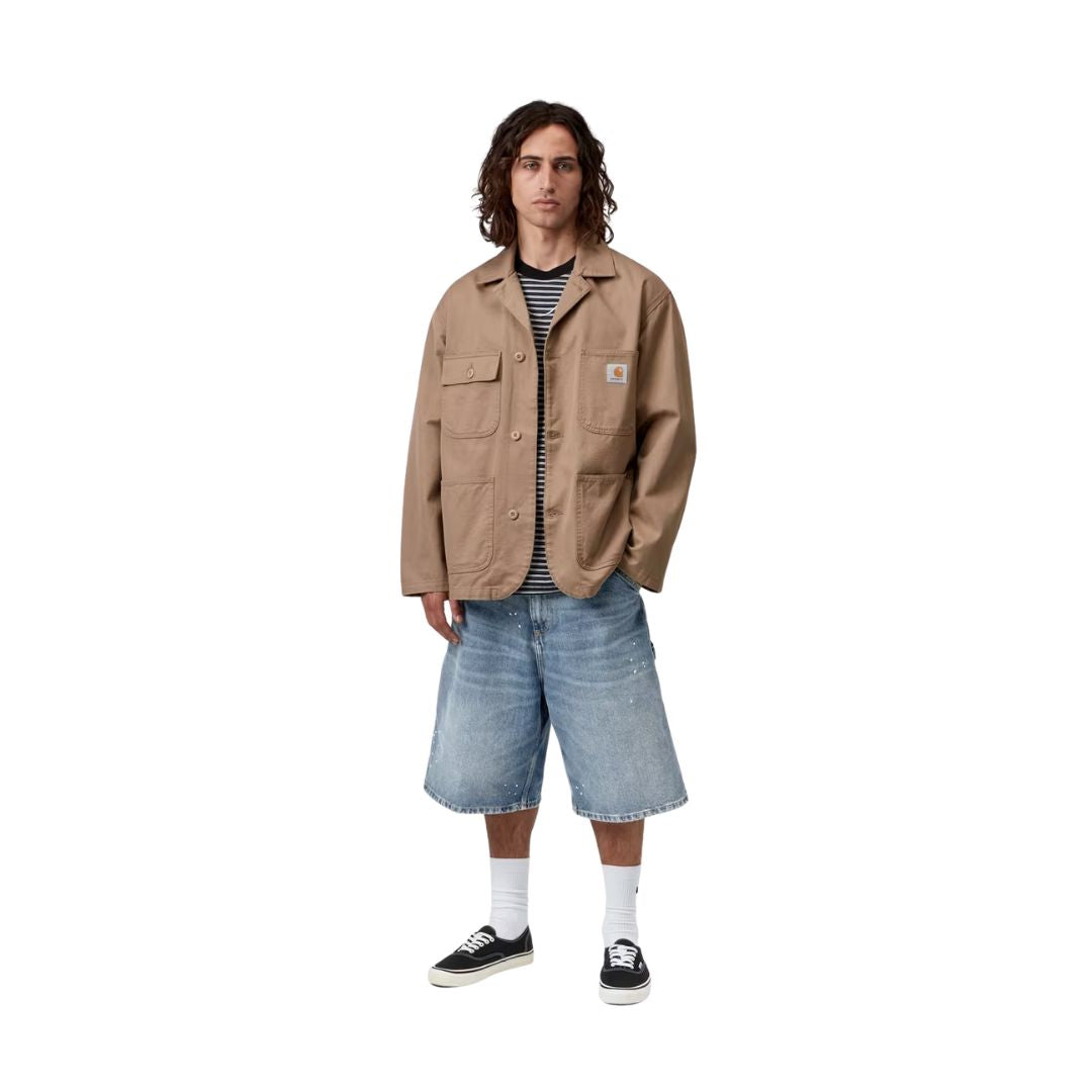 Carhartt WIP OG Single Knee Short azul destroy wash, modelo cuerpo completo vista frontal, wide fit con chaqueta de trabajo y zapatillas Vans.