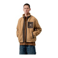 Modelo de frente con la chaqueta forro polar Carhartt WIP Prentis Liner en color WIP Dusty H / Tobacco, de pelo grueso con bolsillo con cremallera en el pecho.
