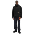 Modelo vistiendo la chaqueta Carhartt WIP Ravon Jacket en color Black Heavy Stone Wash, cierre con cremallera y cuello alto.