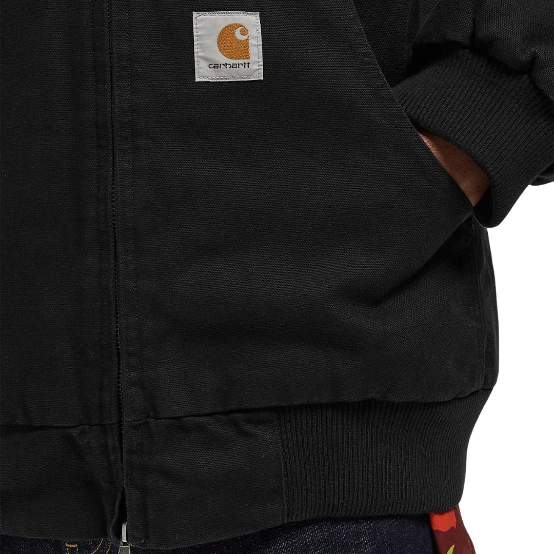Detalle del bolsillo frontal y etiqueta Carhartt WIP en la Ravon Jacket color Black Heavy Stone Wash.