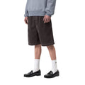 Carhartt WIP Reynold Short Shale Dusky Washed, vista lateral: silueta wide-leg holgada, bajo con costuras en contraste y acabado washed en marrón oscuro.
