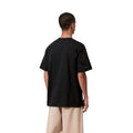 Carhartt WIP S/S Madison T-Shirt black/white, vista trasera sobre modelo con pantalón beige, mostrando la amplitud de espalda y el largo de las mangas cortas.