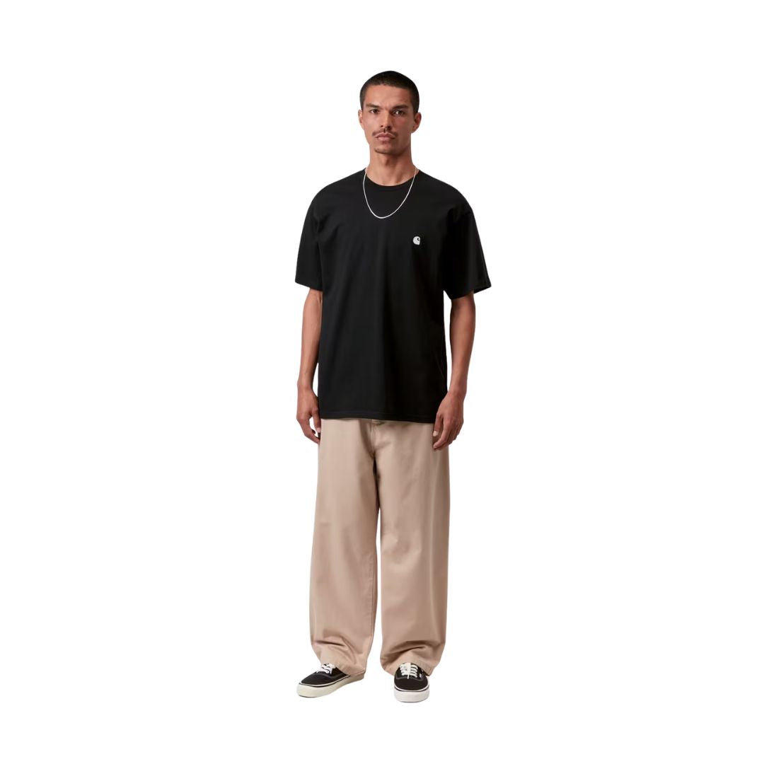 Carhartt WIP S/S Madison T-Shirt black/white combinada en look completo con pantalón ancho beige, mostrando el contraste del logo blanco y la caída loose fit.