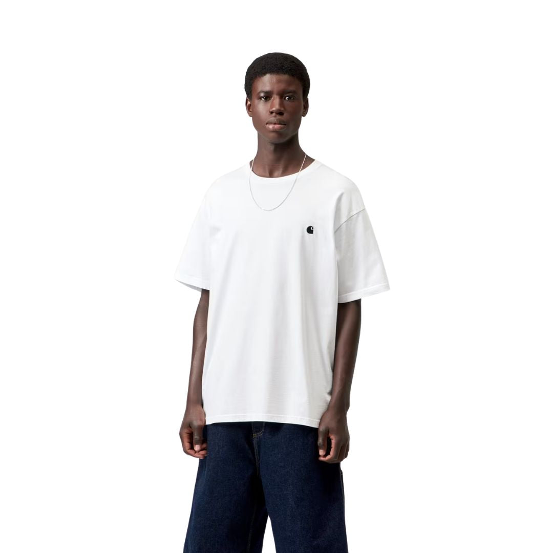 Carhartt WIP S/S Madison T-Shirt white/black en plano frontal sobre modelo, con pantalón vaquero ancho, resaltando el cuello redondo y el logotipo bordado en el pecho.