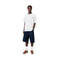 Carhartt WIP S/S Madison T-Shirt white/black combinada en look completo con bermuda vaquera índigo, mostrando el loose fit y la caída de la camiseta sobre el cuerpo.
