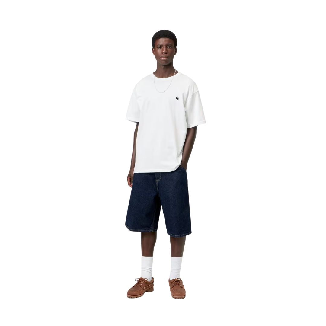 Carhartt WIP S/S Madison T-Shirt white/black combinada en look completo con bermuda vaquera índigo, mostrando el loose fit y la caída de la camiseta sobre el cuerpo.