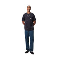 Modelo con pantalón Carhartt WIP Single Knee Pant en denim Blue Marble Used Wash combinado con polo marrón, mostrando el corte holgado y el desgaste marmoleado de la tela.