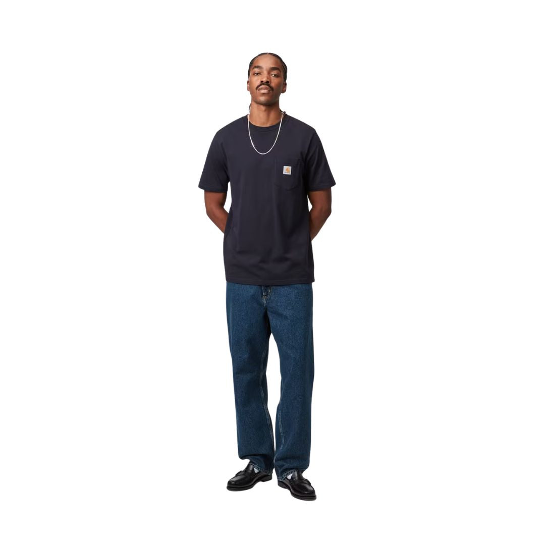 Modelo con pantalón Carhartt WIP Single Knee Pant en denim Blue Marble Used Wash combinado con polo marrón, mostrando el corte holgado y el desgaste marmoleado de la tela.
