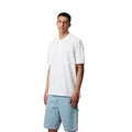 Polo Carhartt WIP Chase Piqué blanco con logo dorado, vista frontal sobre modelo.