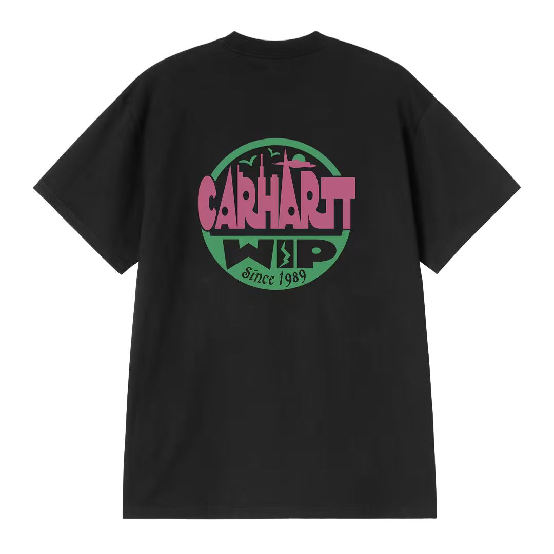 Carhartt WIP S/S Luggage Label T-Shirt negra, vista trasera: gran insignia circular con skyline urbano, logo Carhartt WIP y texto Since 1989 en rosa y verde, corte oversized.